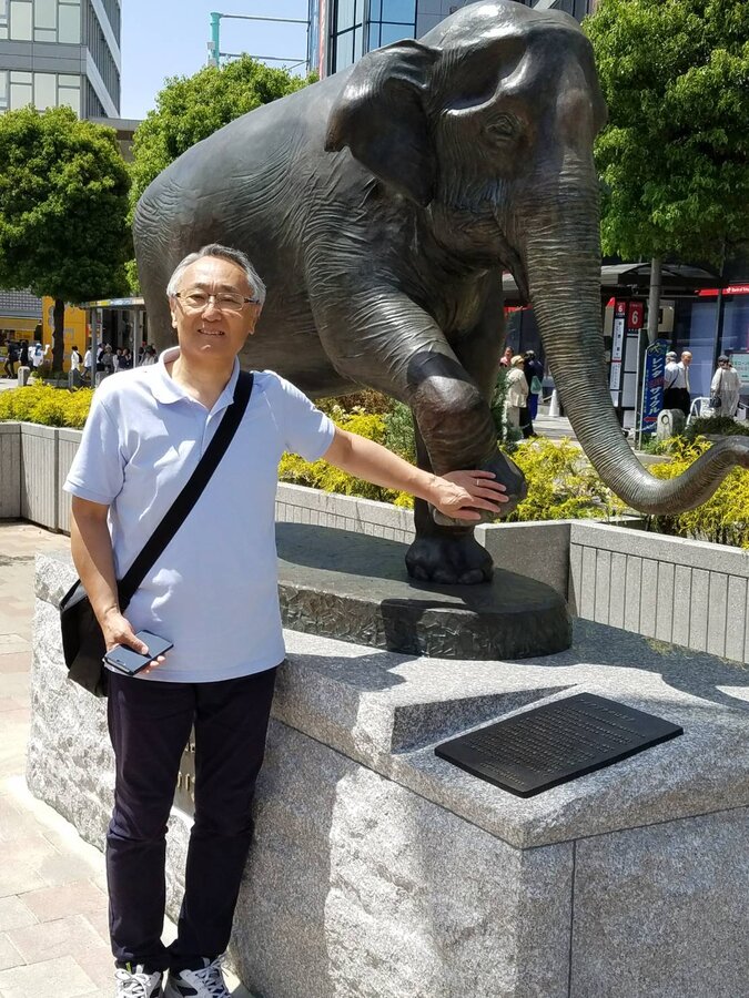 ゾウの像に手を添える岩井俊二